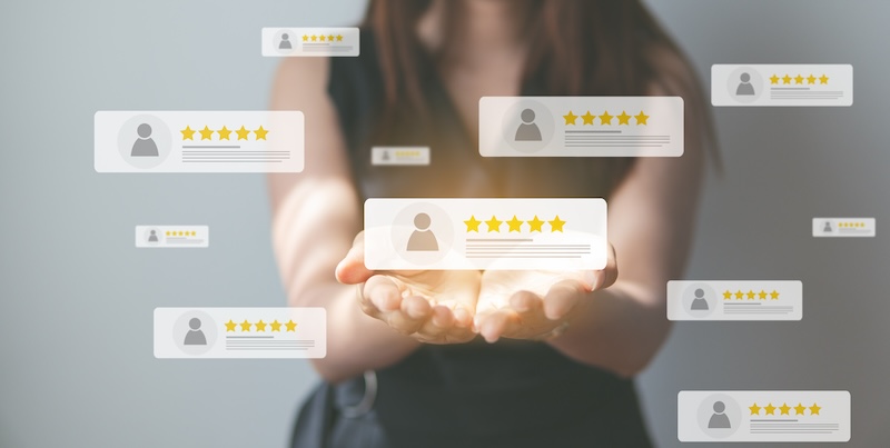 A person holds out their hands, revealing virtual bubbles with user profiles and star ratings. These five-star symbols represent positive feedback, acting as a reputation defender by showcasing exceptional reviews and maintaining a stellar image.