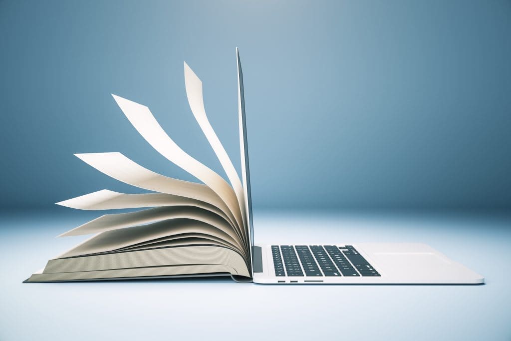 A laptop with a book on it on a blue background.