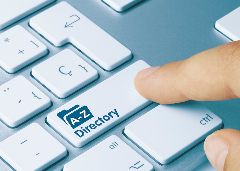 A close-up of a computer keyboard shows a finger pressing a white key labeled with a blue folder icon and the text "A-Z Directory," emphasizing executive privacy. Nearby keys include "ctrl" and various symbols.